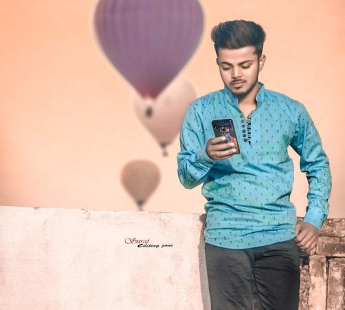 A man standing on a ledge holding a phone.